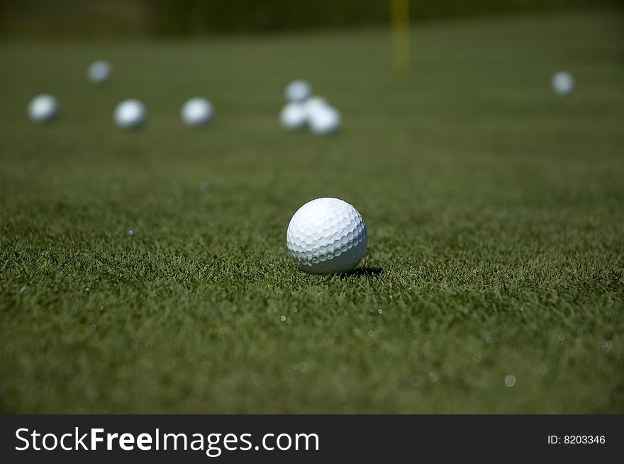 Some golf balls near a hole