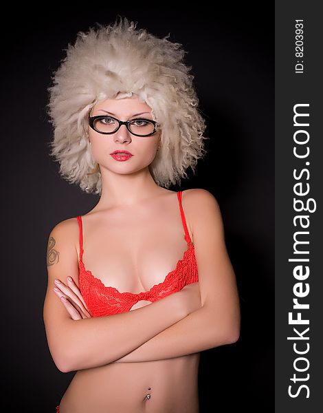 Young girl in glasses and furry hat over black background