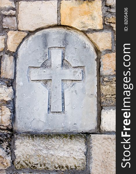 Stone cross built in old wall