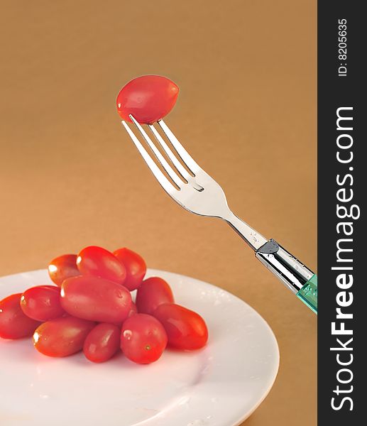 Fork small tomato in brown
background. Fork small tomato in brown
background