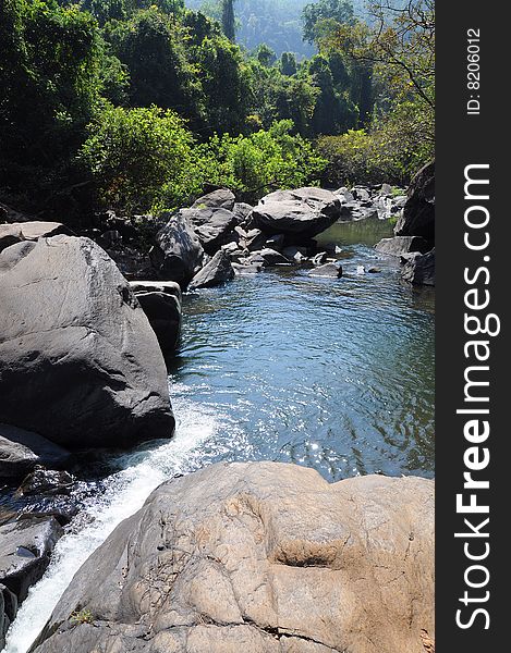 Lake and waterfall in mountains among huge stones and jungle forest. Lake and waterfall in mountains among huge stones and jungle forest