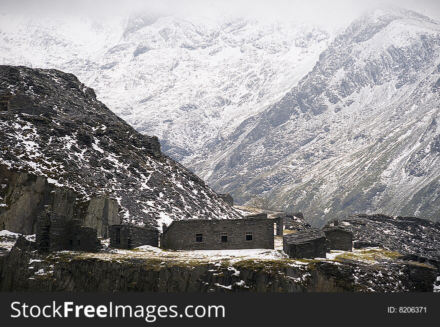 Abandoned buildings in a disused slate quarry in North Wales with a rugged mountain background. Abandoned buildings in a disused slate quarry in North Wales with a rugged mountain background.