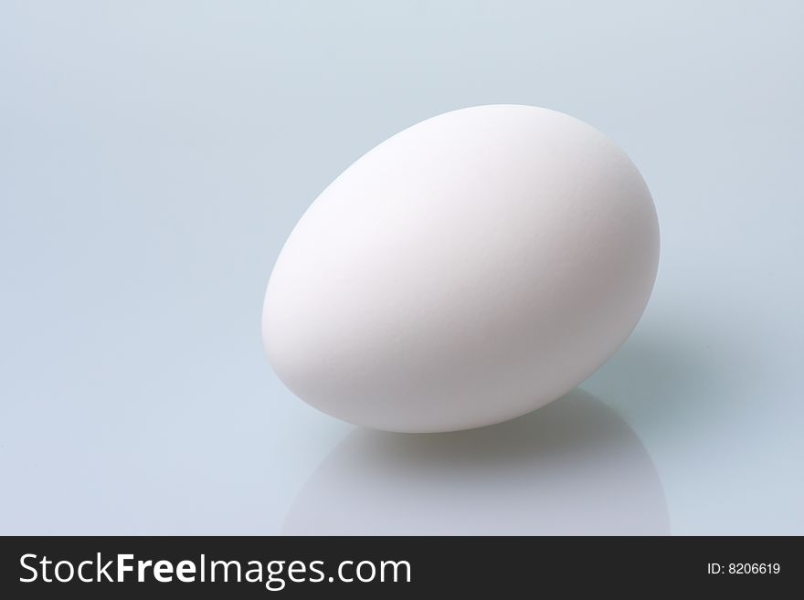 White egg rests on a blue table. White egg rests on a blue table.