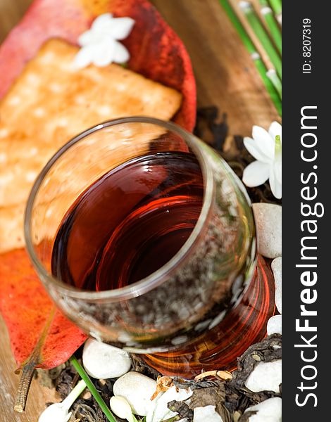 A glass of jasmine tea with ingredients and biscuit on the background - relaxation. A glass of jasmine tea with ingredients and biscuit on the background - relaxation