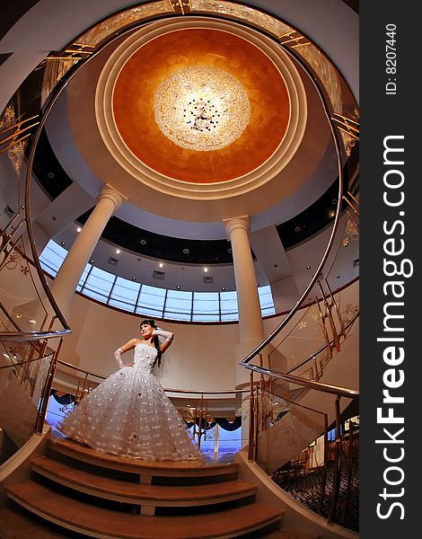 Bride on stairs with large chandelier over her