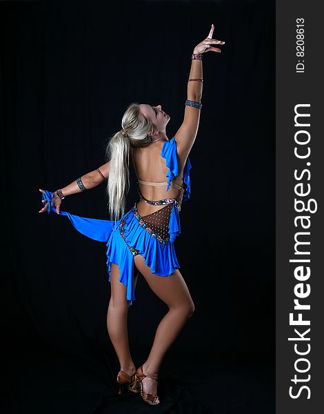 Lovely blondie girl latino dancer in blue dress against black background