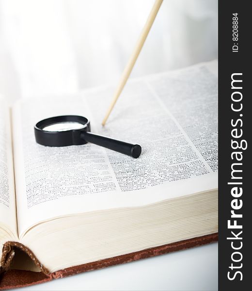 The magnifier lays on the open book. The magnifier lays on the open book