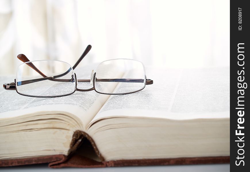 Glasses lay on the big old book. Glasses lay on the big old book