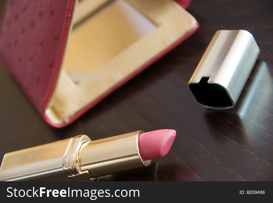 Rouge lipstick with pocket mirror on brown. Rouge lipstick with pocket mirror on brown