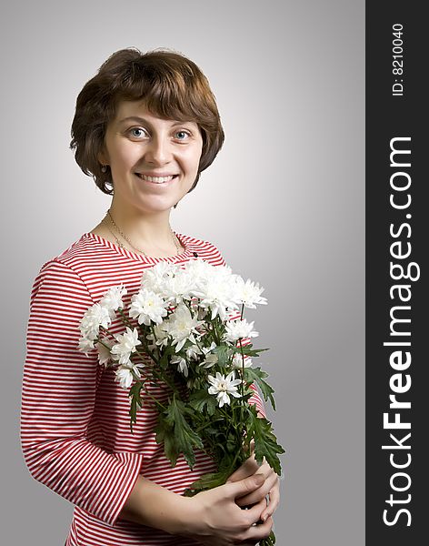 There is a happy woman with white flowers in the hands. There is a happy woman with white flowers in the hands