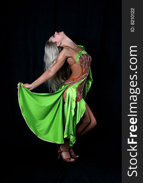 Blondie girl latin dancer in green dress  against black background