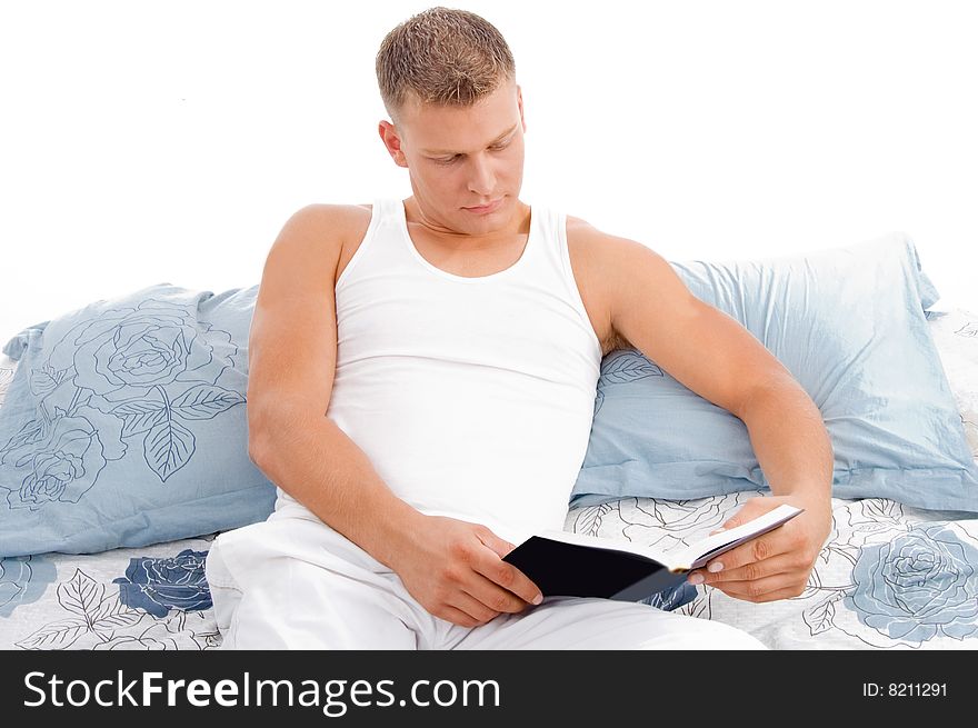 Handsome male reading book in bed with white background. Handsome male reading book in bed with white background