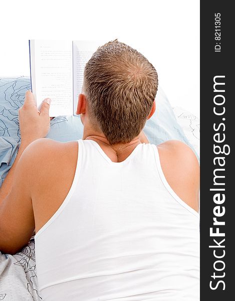Man reading book while resting on matress bed