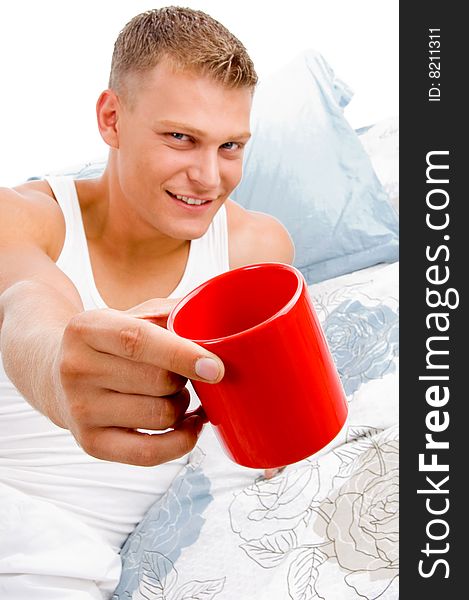 Male showing coffee mug to camera in bed