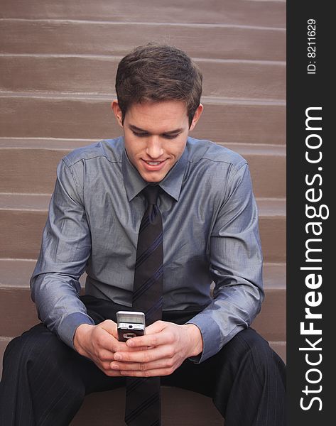 Business Man checking messages on phone sitting down on steps