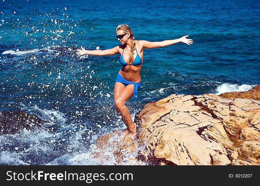 Happy beautiful blonde standing on the rocky beach. Happy beautiful blonde standing on the rocky beach