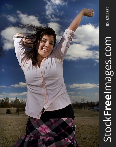 A teen expresses her exuberance against a brilliant sky. A teen expresses her exuberance against a brilliant sky.