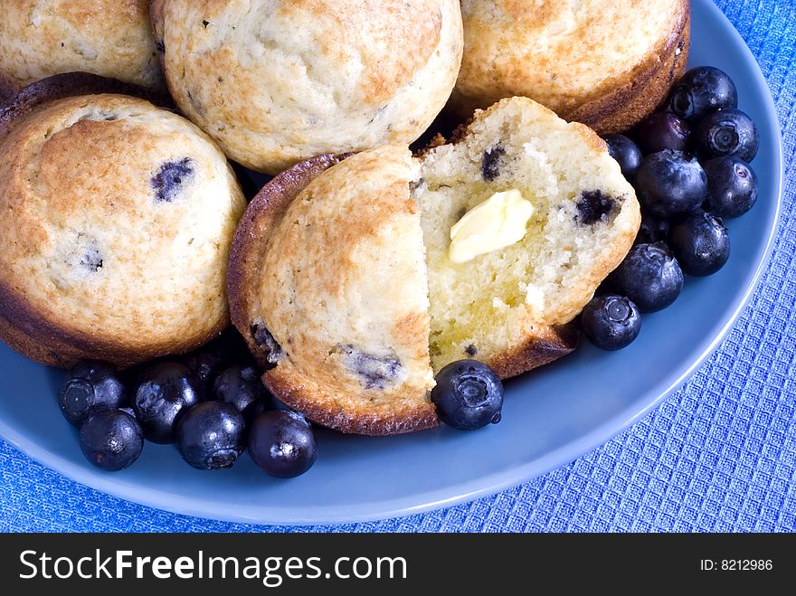 Hot Blueberry Muffins with melting butter on a blue plate copy space. Hot Blueberry Muffins with melting butter on a blue plate copy space