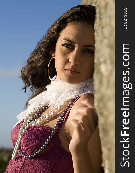 A young brazilian brunette wearing a dark red bustier by some rocks. A young brazilian brunette wearing a dark red bustier by some rocks.