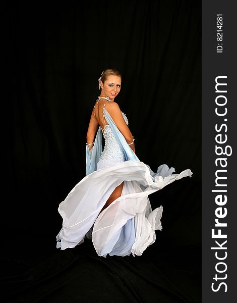 Dancer in classical blue-white dress against black background