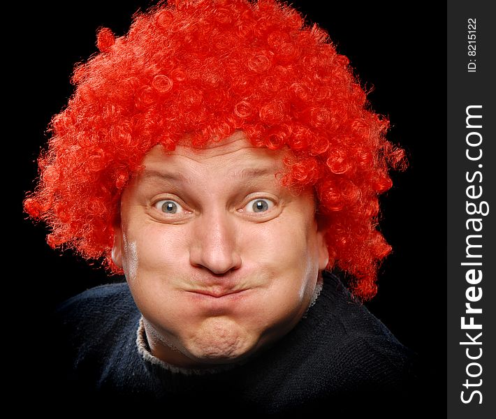 Close up shot of a man in clown's wig having fun, making faces and showing his tongue, isolated on black background. Close up shot of a man in clown's wig having fun, making faces and showing his tongue, isolated on black background