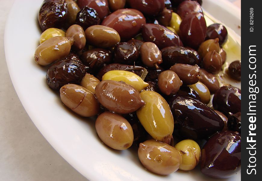 Green, brown and black olives in oil in a bowl