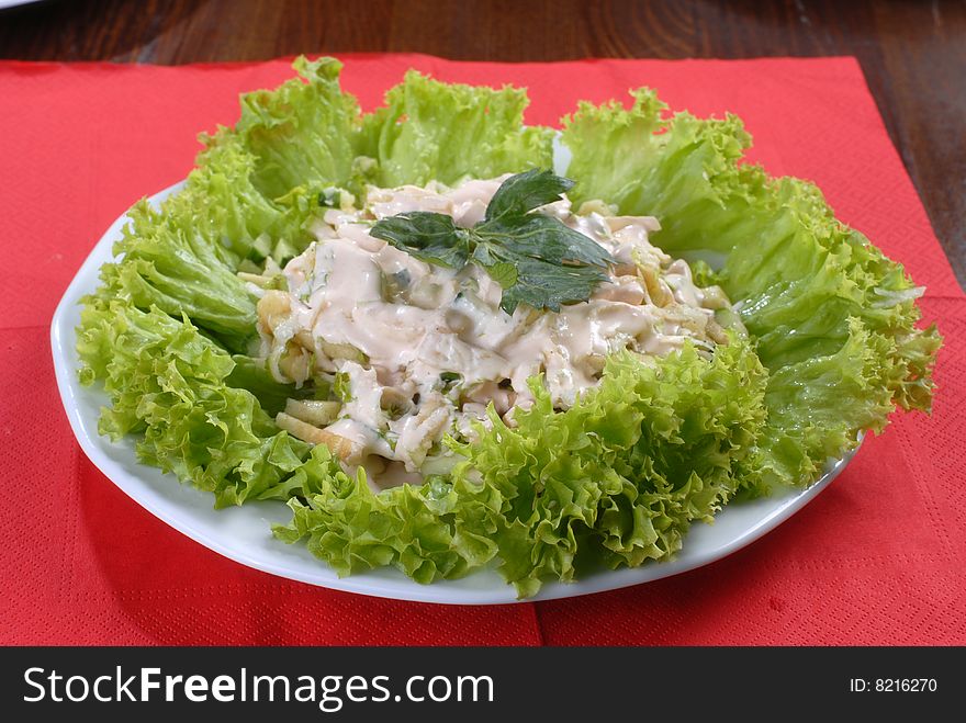 A plate of tasty juicy salad served with sause and decortaed with lettuce. A plate of tasty juicy salad served with sause and decortaed with lettuce