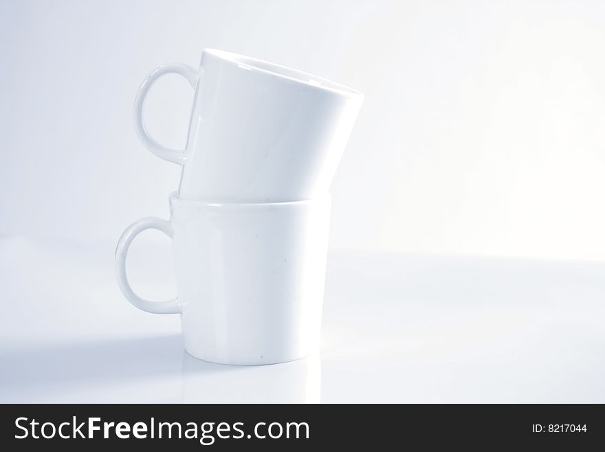 Two white porcelain mugs stacked on top of each other. Two white porcelain mugs stacked on top of each other