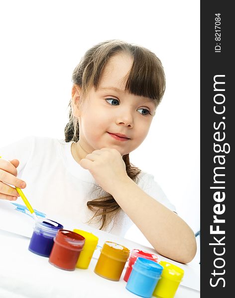 Cute dreamy little girl sitting by the table and painting with watercolor. Cute dreamy little girl sitting by the table and painting with watercolor