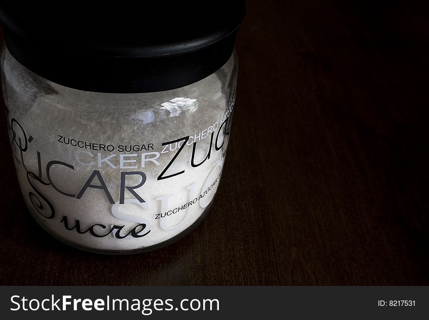 A jar of white sugar on a wooden table