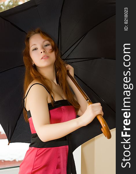 Beautiful young woman with umbrella in room