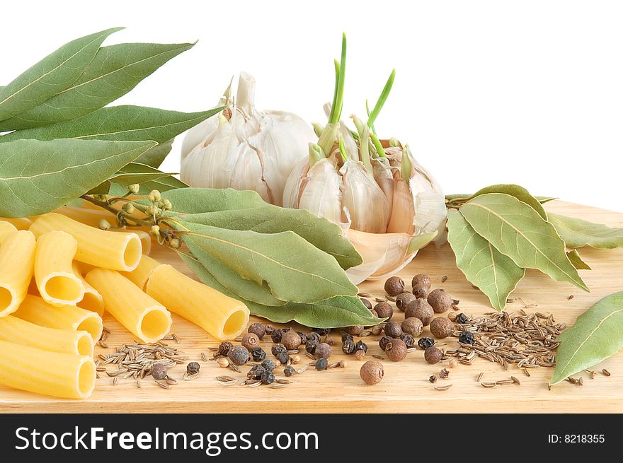 Macaroni with fresh bay leaves, garlic, whole black pepper and caraway seeds on wooden cutting board. Macaroni with fresh bay leaves, garlic, whole black pepper and caraway seeds on wooden cutting board