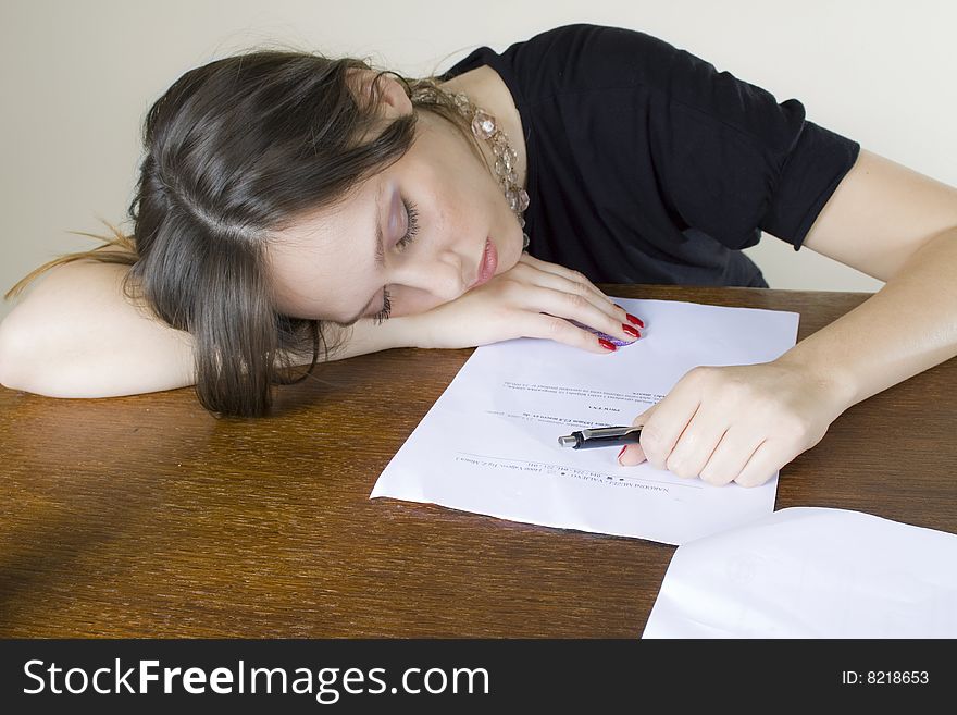 Photo of a young, attractive girl on an office table, asleep, being too tired to continue her work. Photo of a young, attractive girl on an office table, asleep, being too tired to continue her work