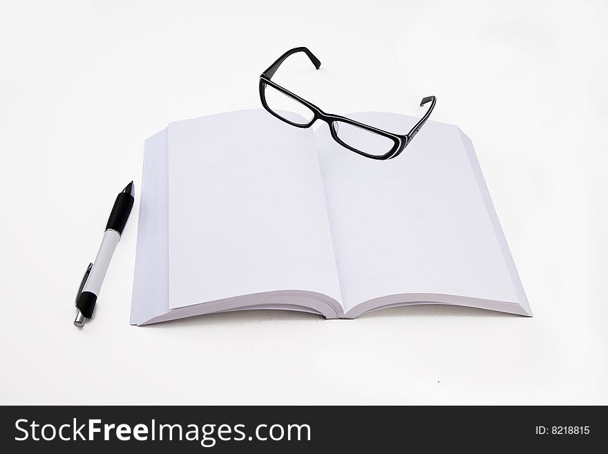A blank pages book with a pen and eyeglasses. A blank pages book with a pen and eyeglasses