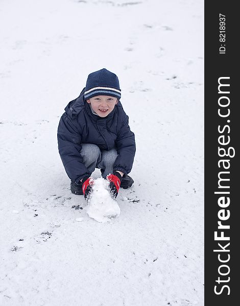 Child playing in the snow he is wearing hat and gloves. Child playing in the snow he is wearing hat and gloves