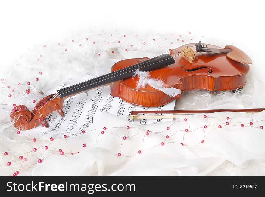 Violin and notes on white silk background with boa and furs