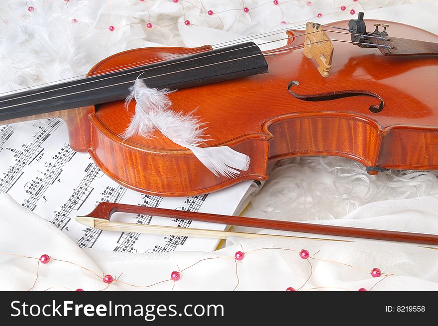 Violin and notes on white silk background with boa and furs