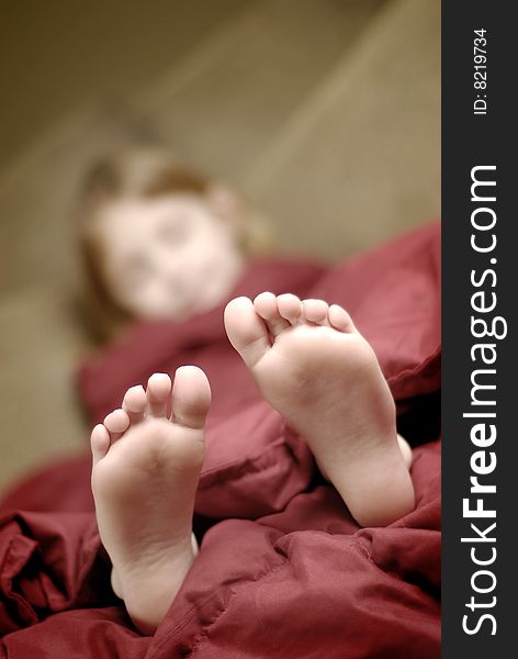 Little girl sleeping with feet poking out of blankets