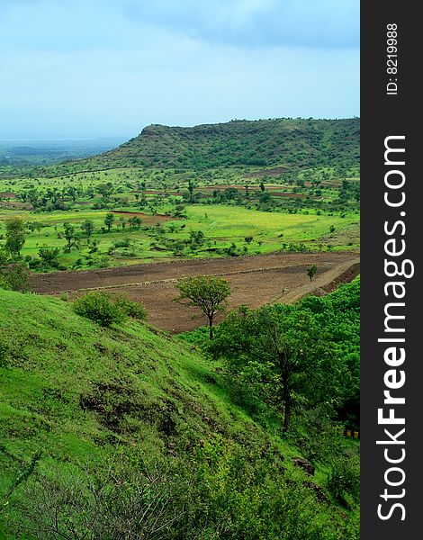 A beautiful landscape scene with vibrant green fields and distant mountain. A beautiful landscape scene with vibrant green fields and distant mountain.