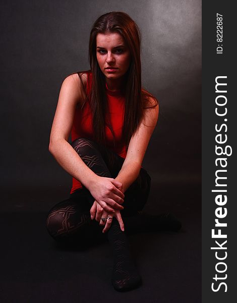 Young attractive girl in the soft studio light sitting on the floor. Young attractive girl in the soft studio light sitting on the floor