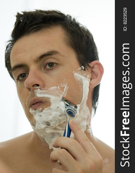 Young man shaving in the morning looking into mirror