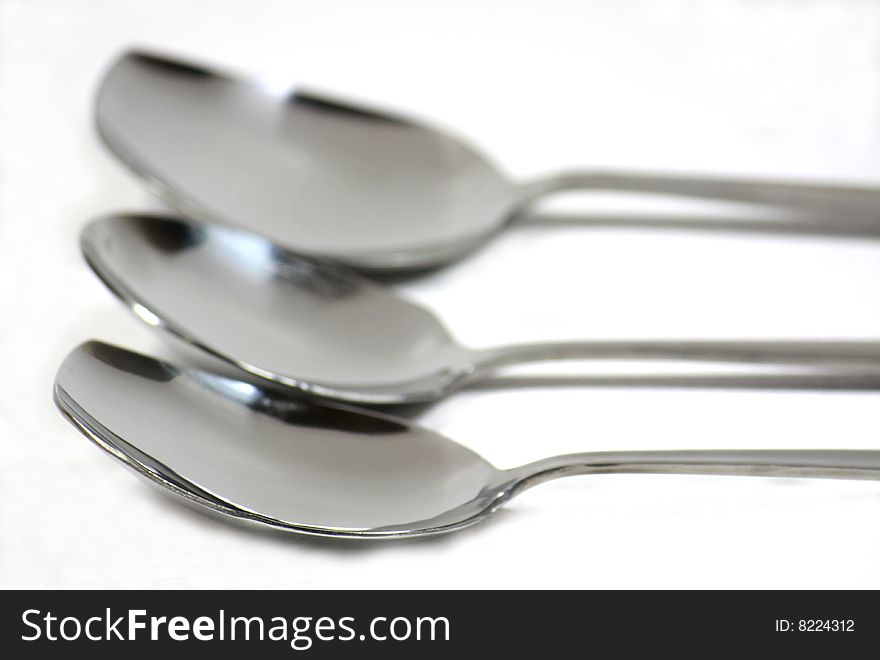 Row of stainless steel spoons isolated on white. Row of stainless steel spoons isolated on white