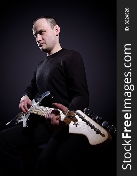 Musician playing guitar on black background