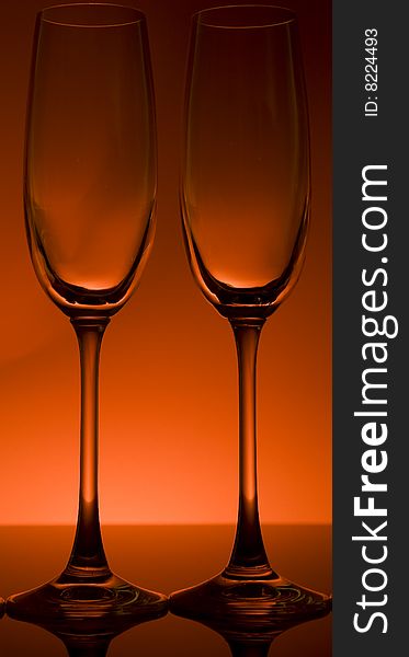 Wine and champagne glasses backlit in front of a red wall