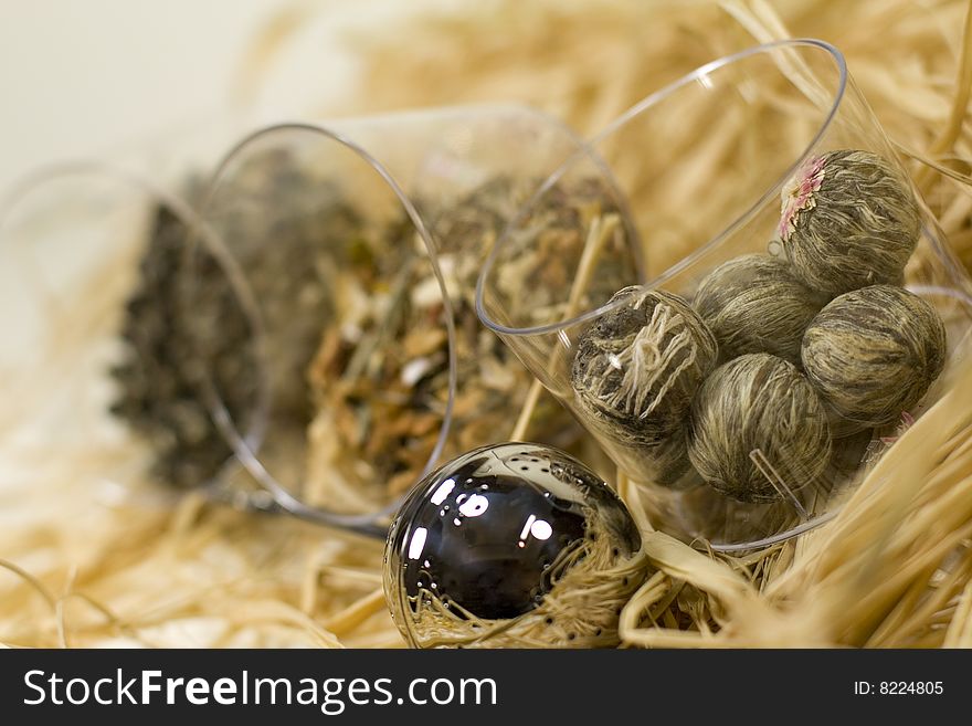 Silver tea-strainer and tree kinds of tea on strow