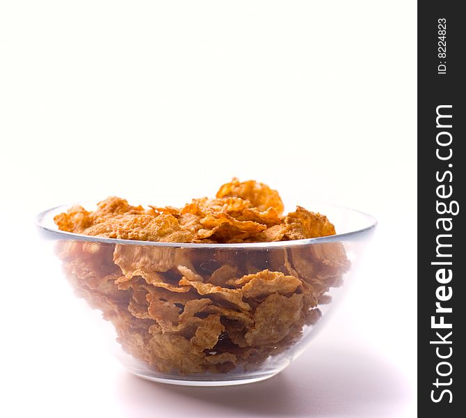 Glass bowl full of cornflakes on white