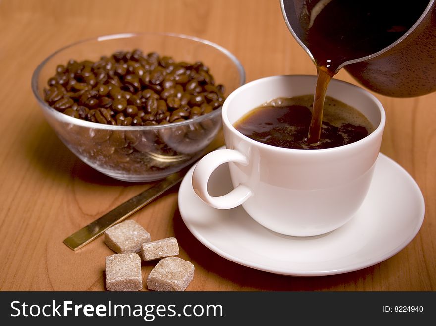 Cup of coffee, sugar and beans in glass bowl on wooden table