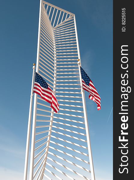 Two American flags frame a tall monument.
