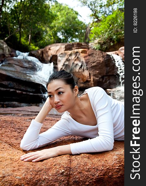 Outdoor waterfall young woman relaxing on the rock. Outdoor waterfall young woman relaxing on the rock