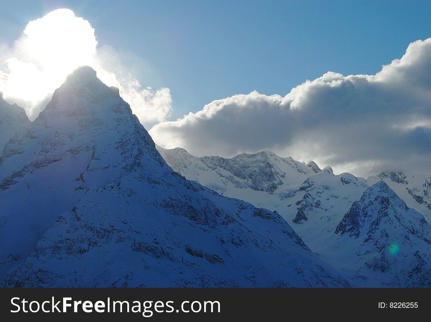 Snow Covered Steeply Rocks And Bright Sky Sunset